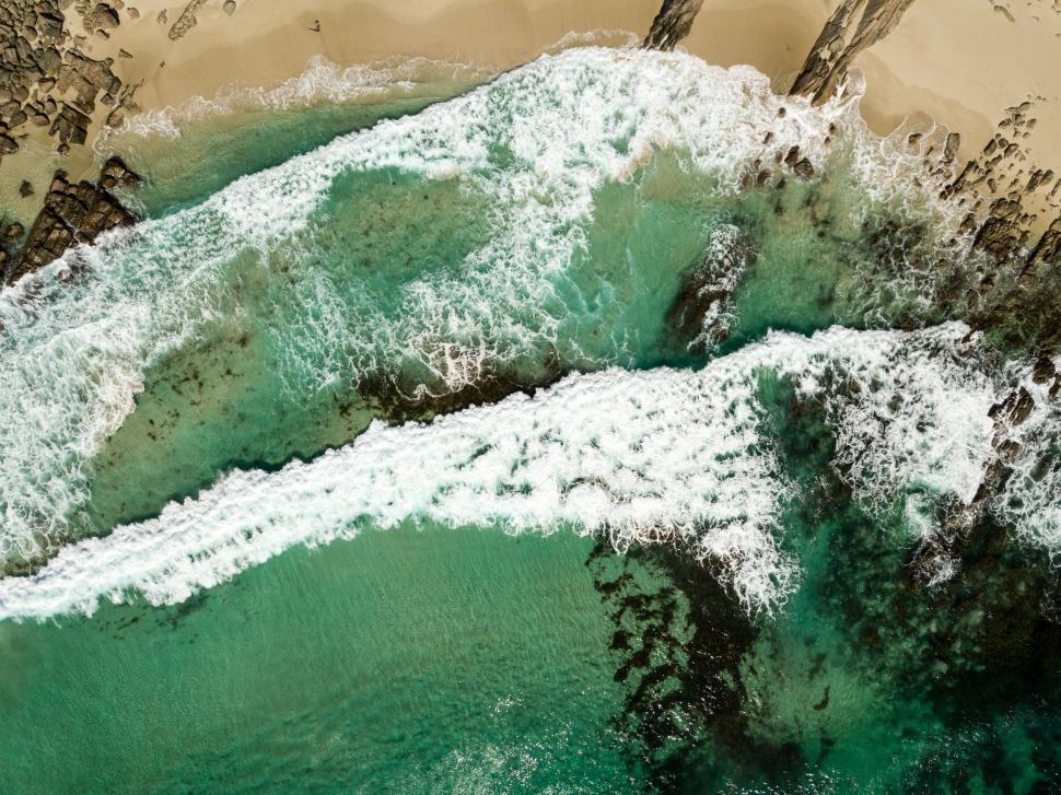 Free Image of Aerial view of ocean waves on an empty beach.  
