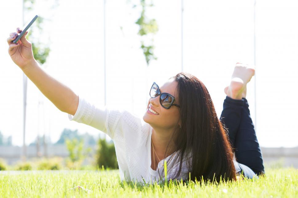Free Image of Beautiful woman on the grass taking selfie 