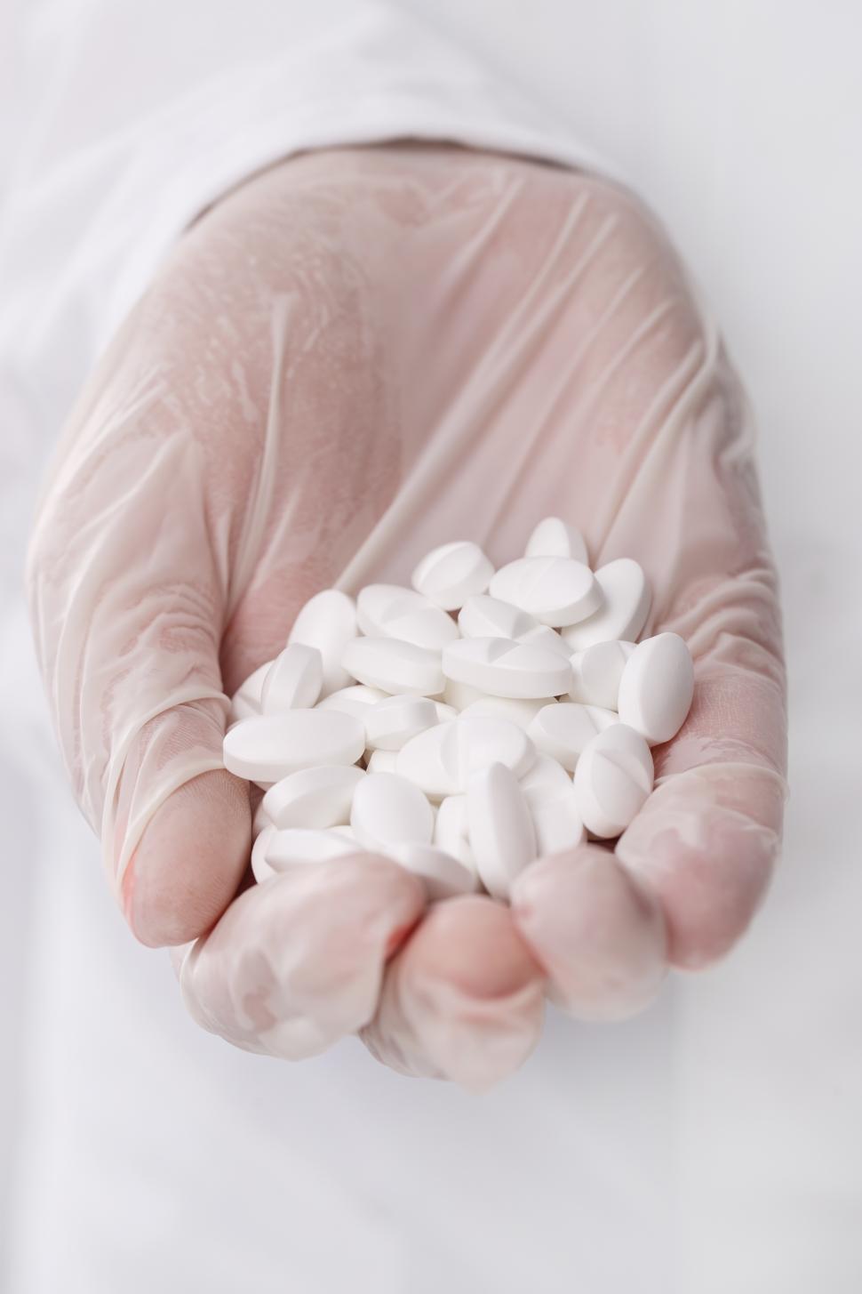 Free Image of Doctor holding heap of white pills 