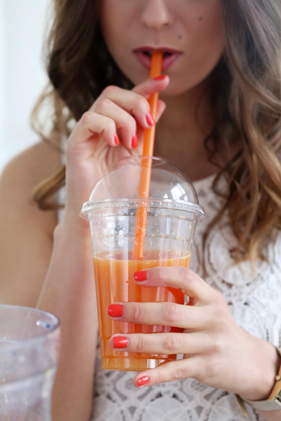 Free Image of Woman sipping orange juice 