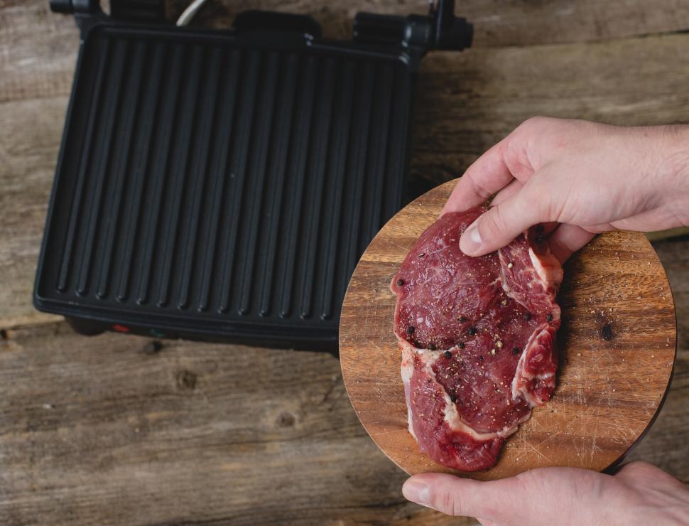 Free Image of Man with steak headed towards indoor grill 