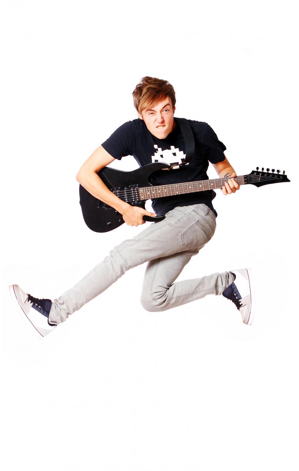 Free Image of Young teenager jumping in the air with a guitar 