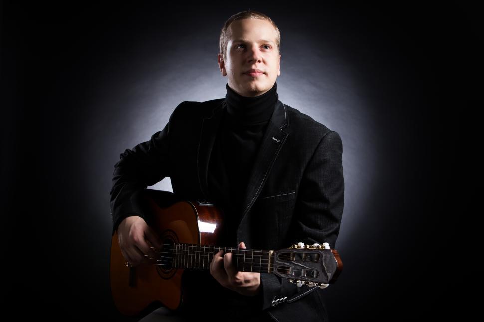 Free Image of Music. Young musician in black suit holding a guitar 
