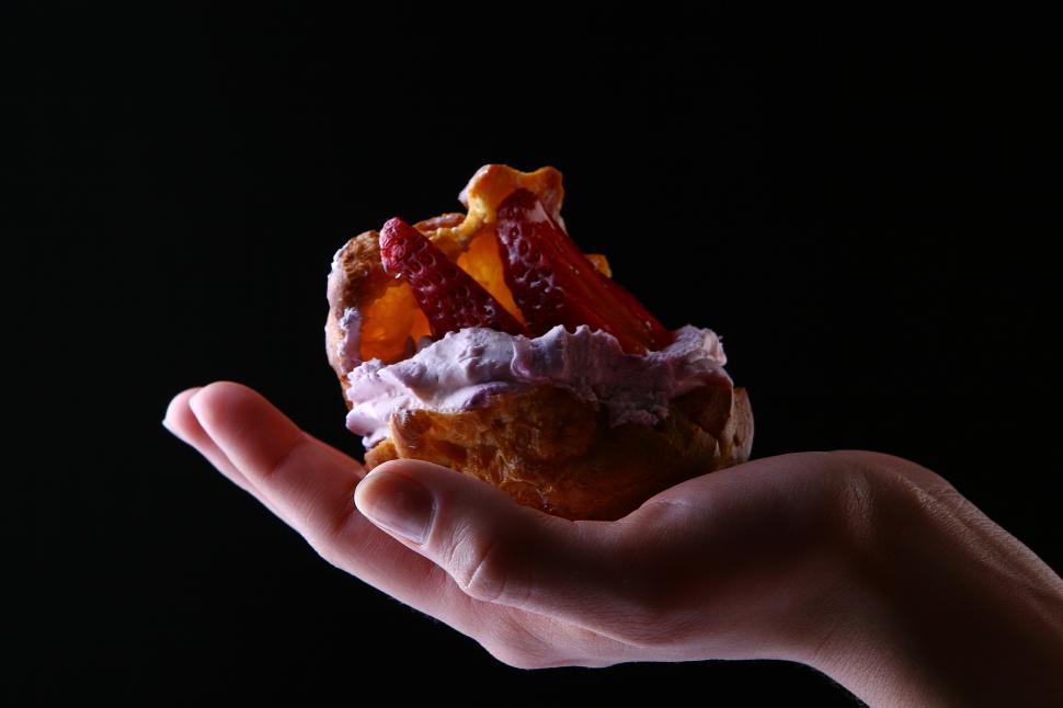 Free Image of hand with fruitcake on dark background 