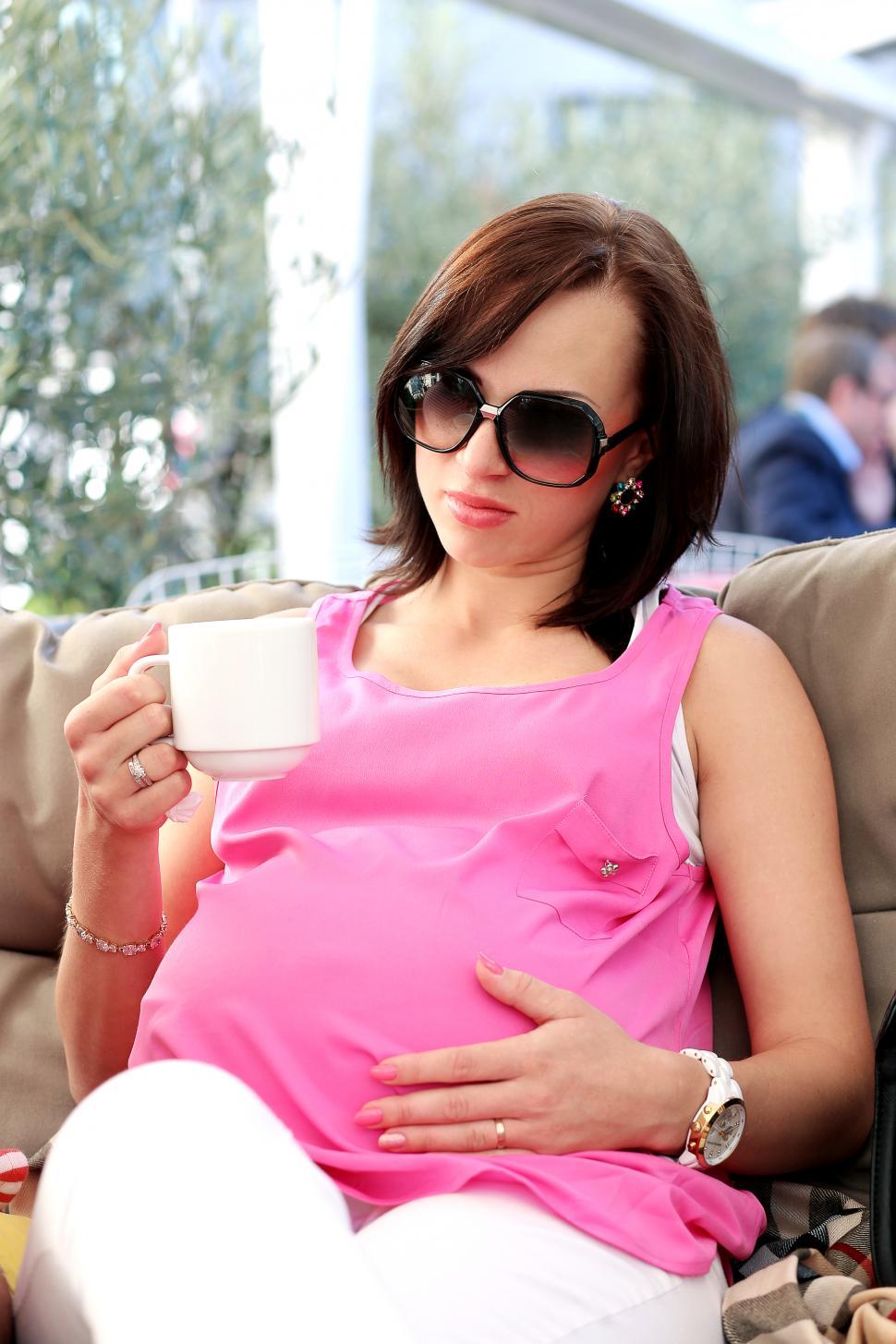 Free Image of Beautiful pregnant woman with a cup sitting in the cafe 