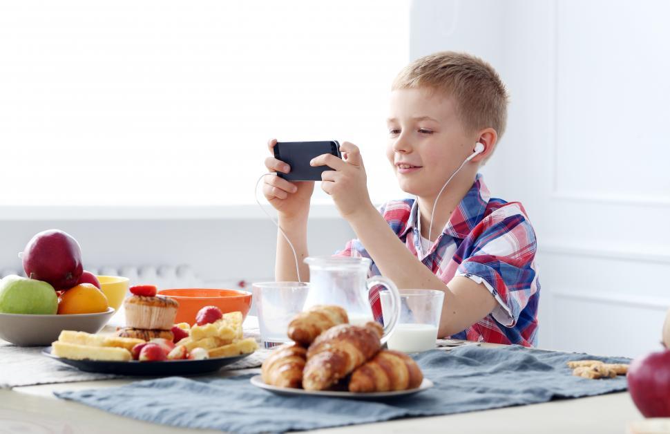 Free Image of Young boy at the table on his phone 
