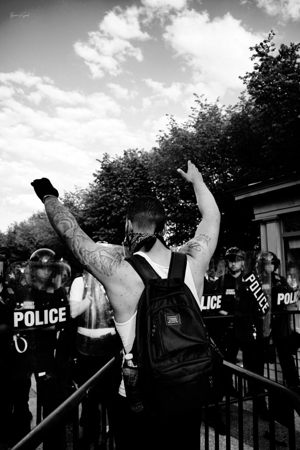 Free Image of Protester facing police line, black and white 