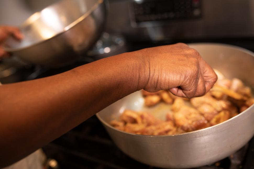 Free Image of Hand and meat pieces in frying pan 