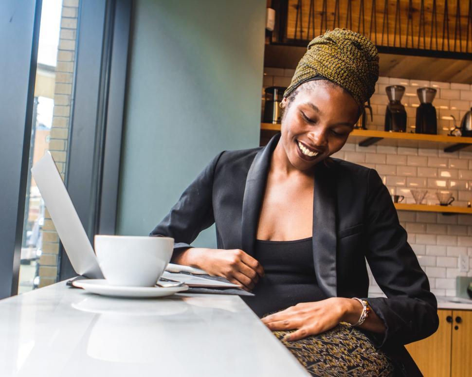 Free Image of Smiling Young Woman in black blazer with laptop in Coffee Shop 