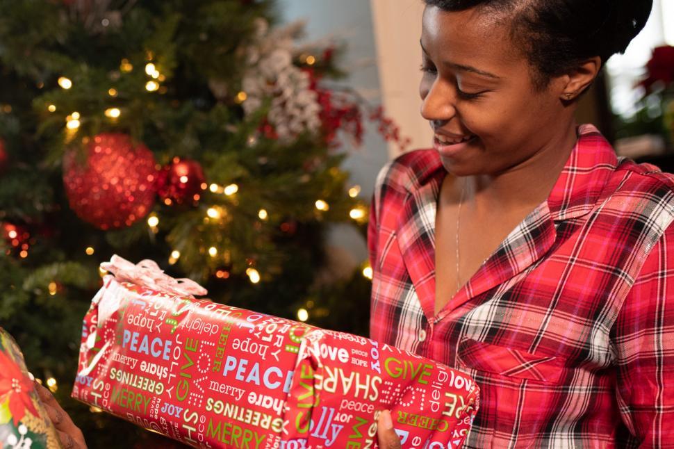 Free Image of Young Smiling Woman and Xmas present with christmas tree in the 
