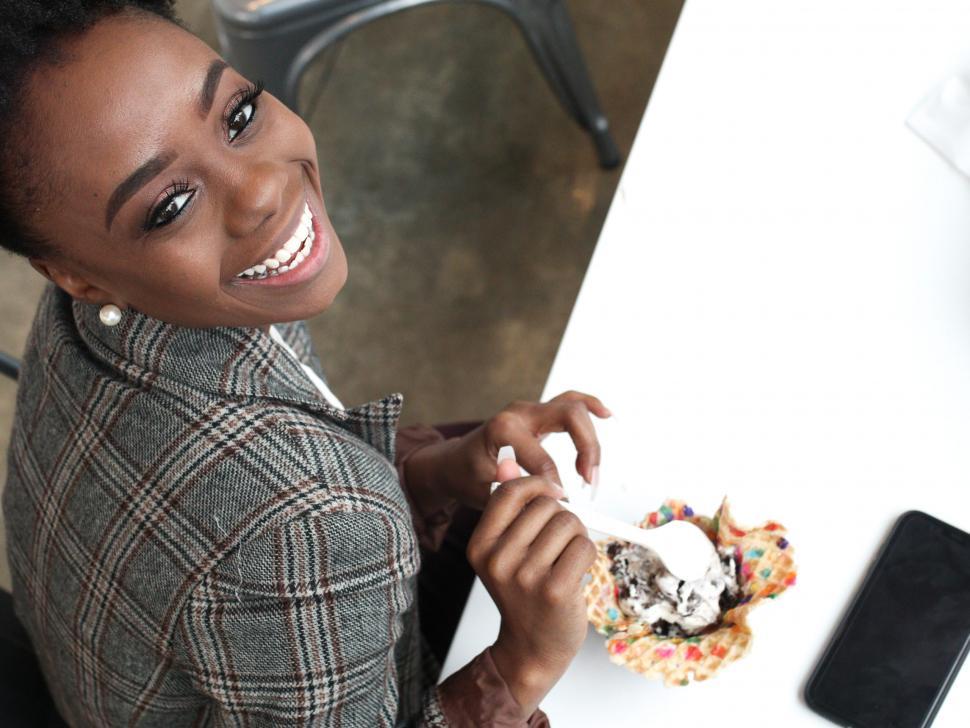 Free Image of Young business woman in tweed blazer eating ice cream with spoon 