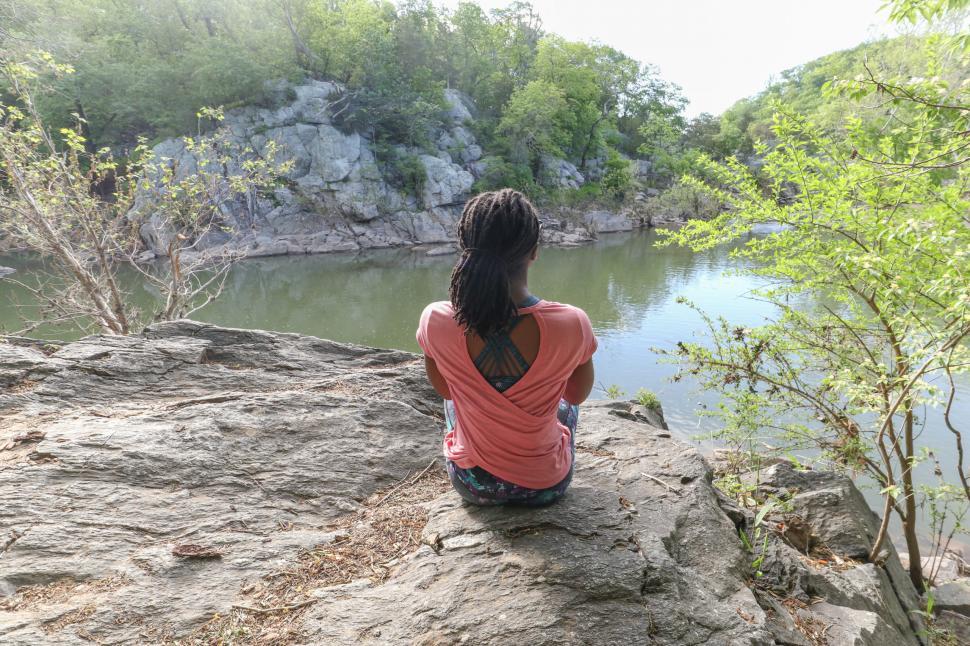 Free Image of Back View of Young Woman sitting near lake 