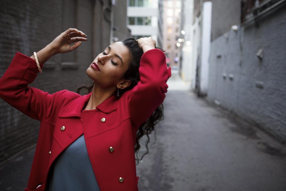 Free Image of Female Fashion Model in Red Coat with hand on hair 