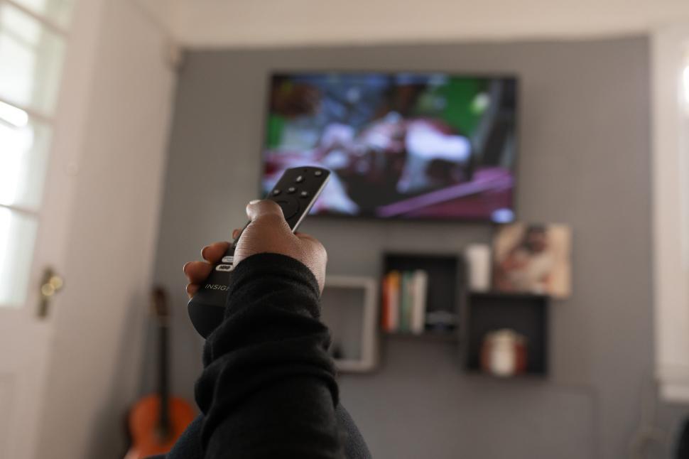 Free Image of TV Remote Control in Hand while watching television at home 