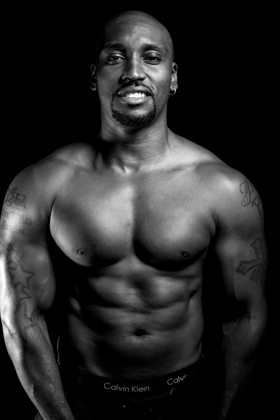 Free Image of Dark background view of Male Bodybuilder smiling and looking at camera 