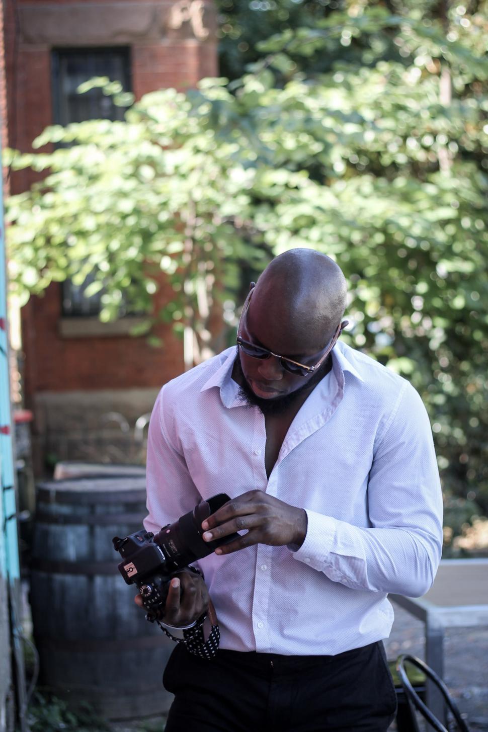 Free Image of Young Photographer in white shirt holding professional camera 