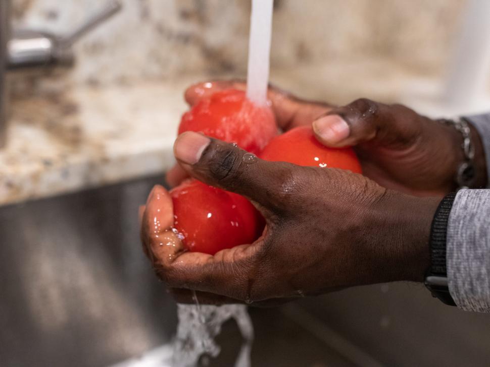 Free Image of Young Man Hands holding tomatoes under running water 