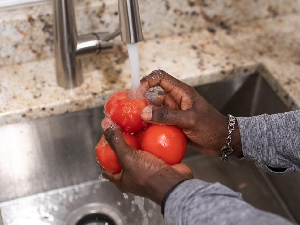 Free Image of Hands and tomatoes under running water 