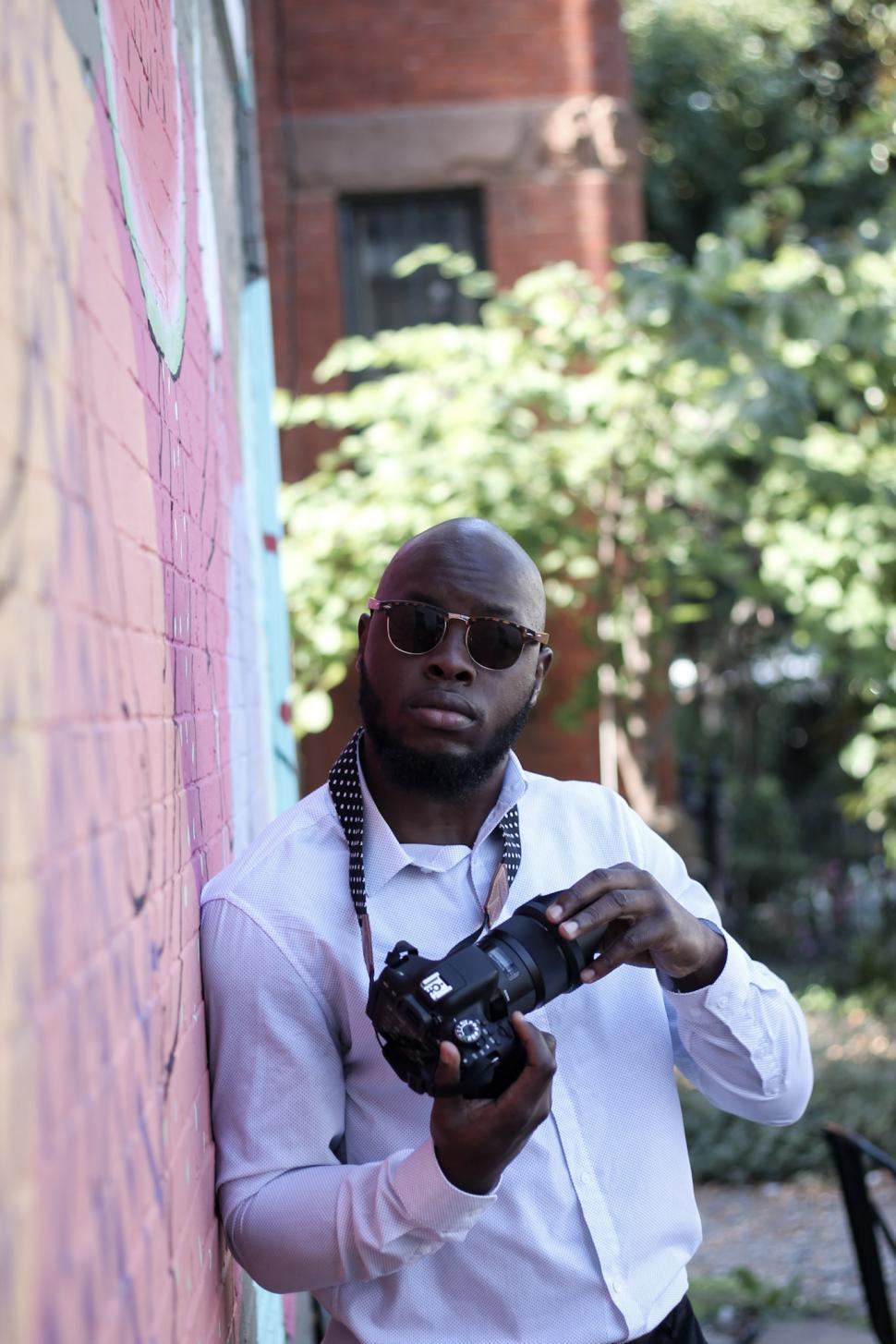 Free Image of Young Bald Man in white shirt holding professional camera - look 
