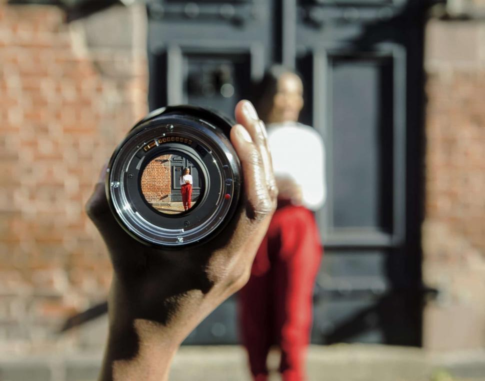 Free Image of Young woman in red trousers with camera lens 