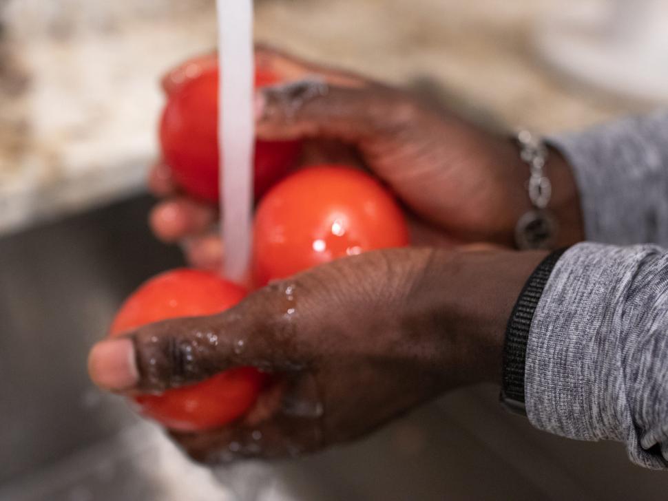 Free Image of Young Man cleaning tomatoes under tap water 