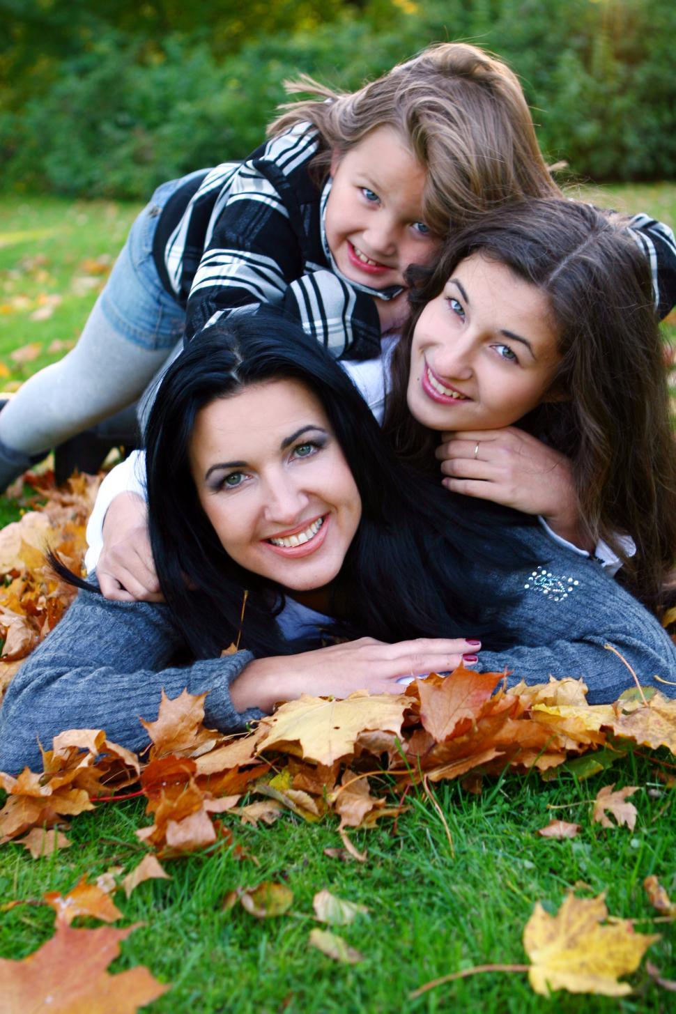 Free Image of Young family piled together in park with fallen leaves 