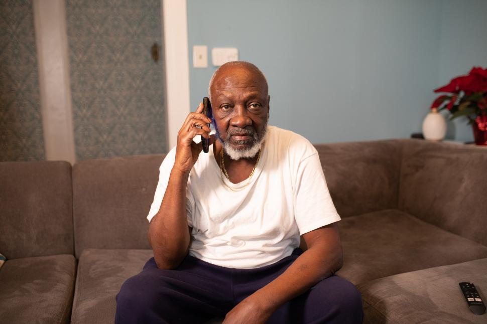 Free Image of Man Talking on Mobile phone sitting at home - looking at camera 