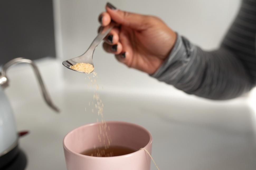 Free Image of Unrecognizable Woman Hand adding sugar into tea cup 
