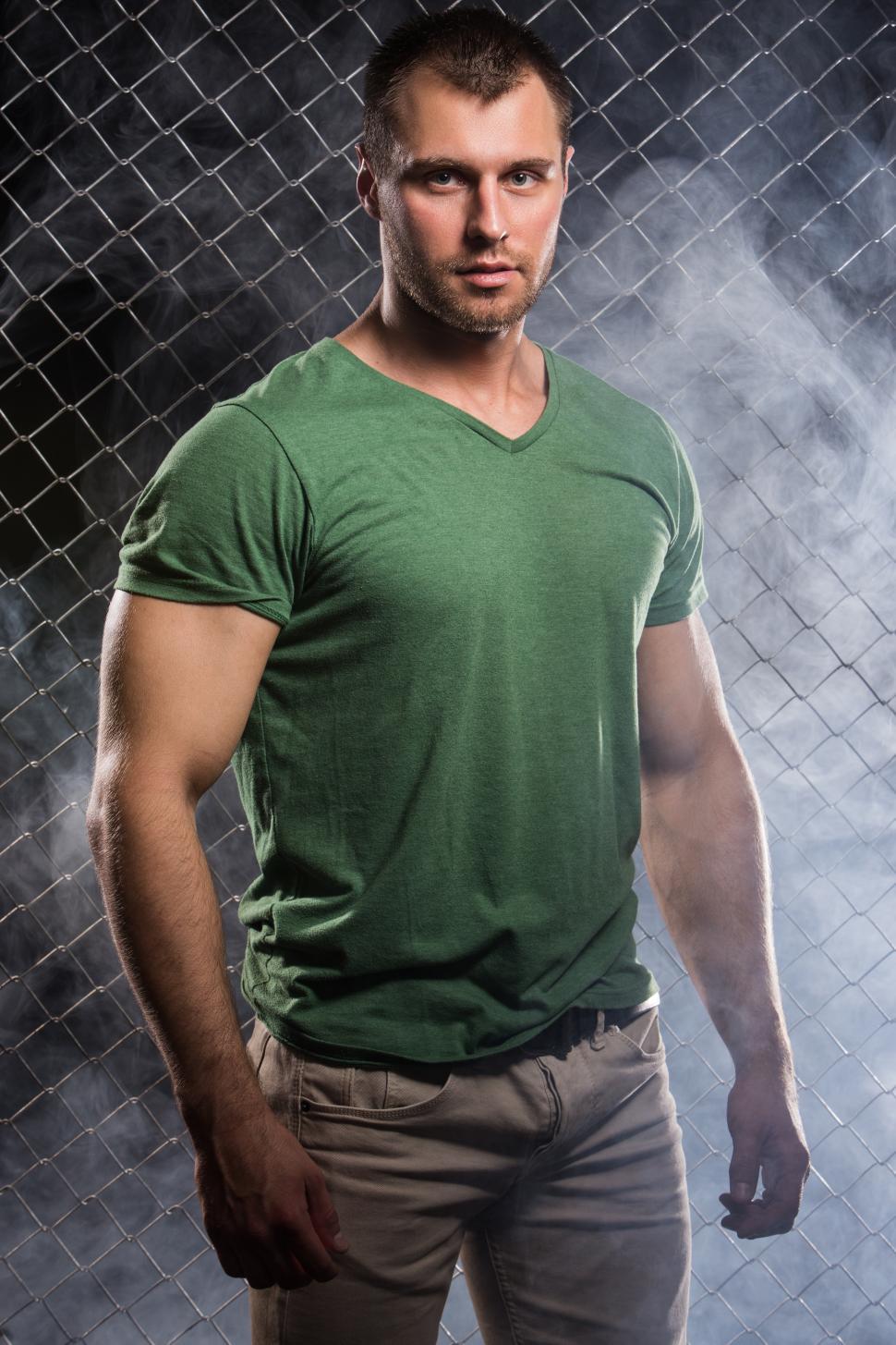 Free Image of Fitness. Beautiful, strong man in clothes on fence background 