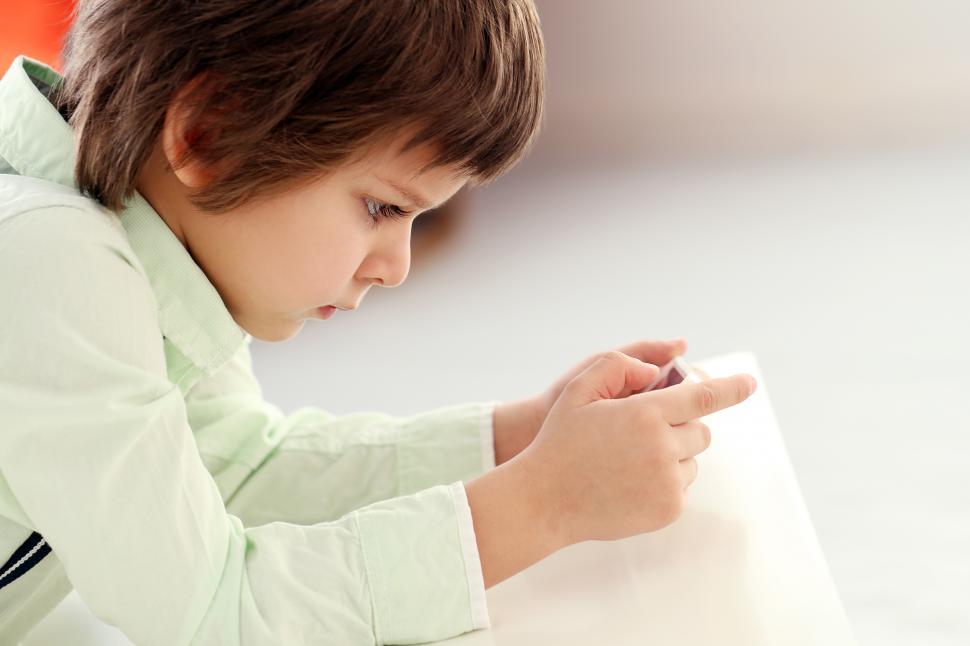 Free Image of Adorable kid plays with electronic device 