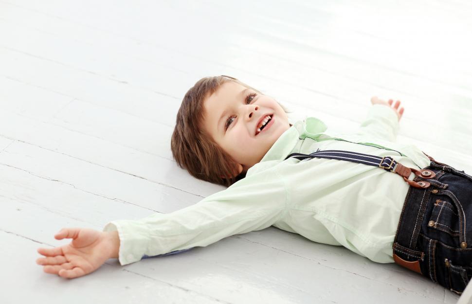 Free Image of Adorable kid, arms wide on the floor 