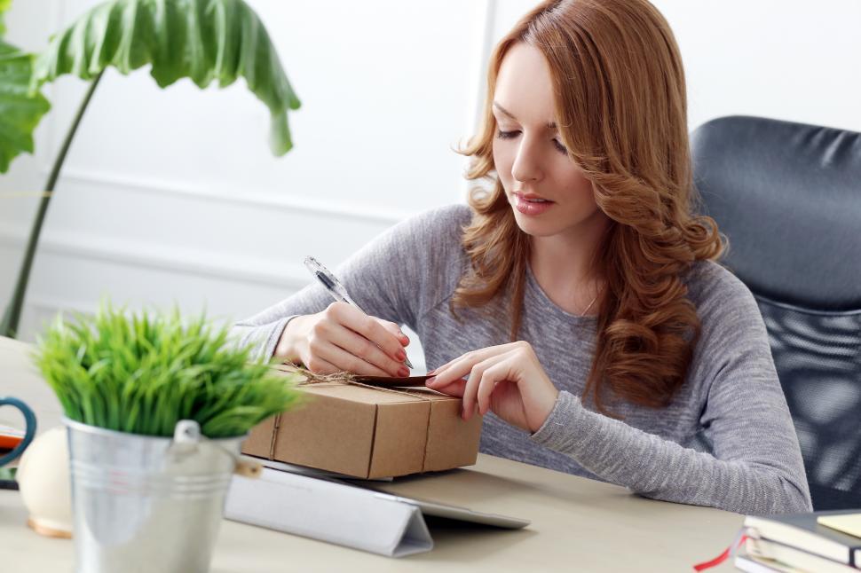Free Image of Lifestyle. Woman writing on tag with package 