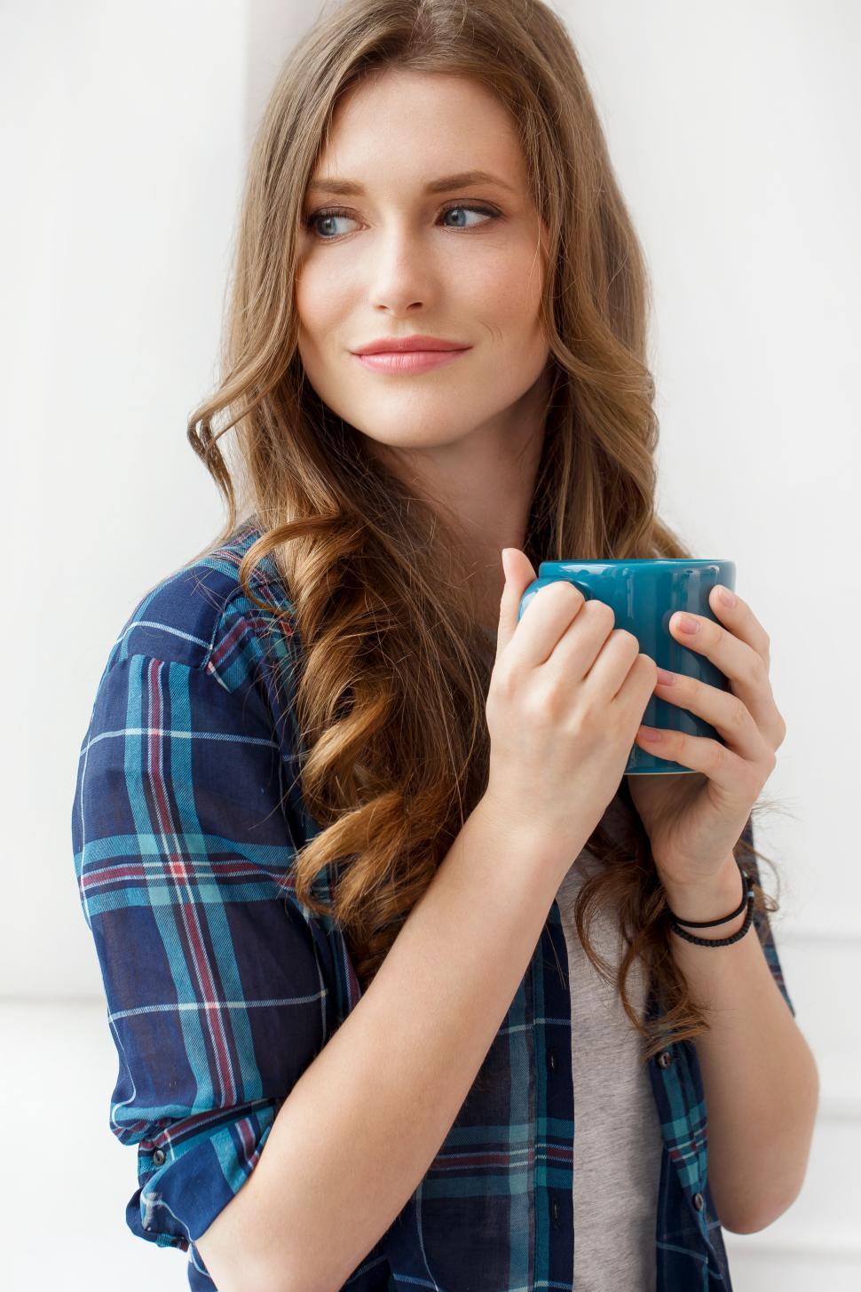 Free Image of Attractive girl looking out the window, holding mug 