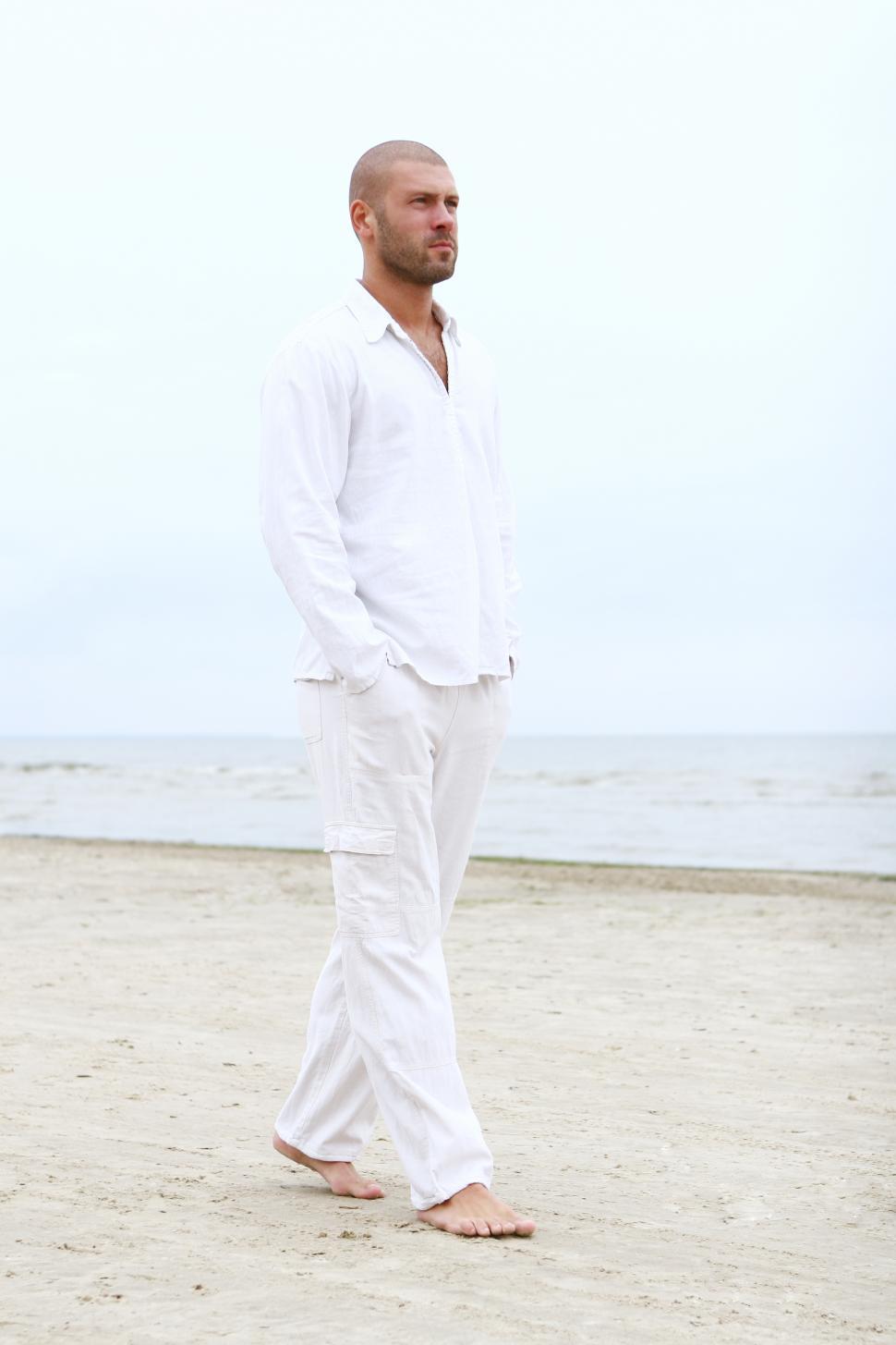 Free Image of Man in white walking on the beach 