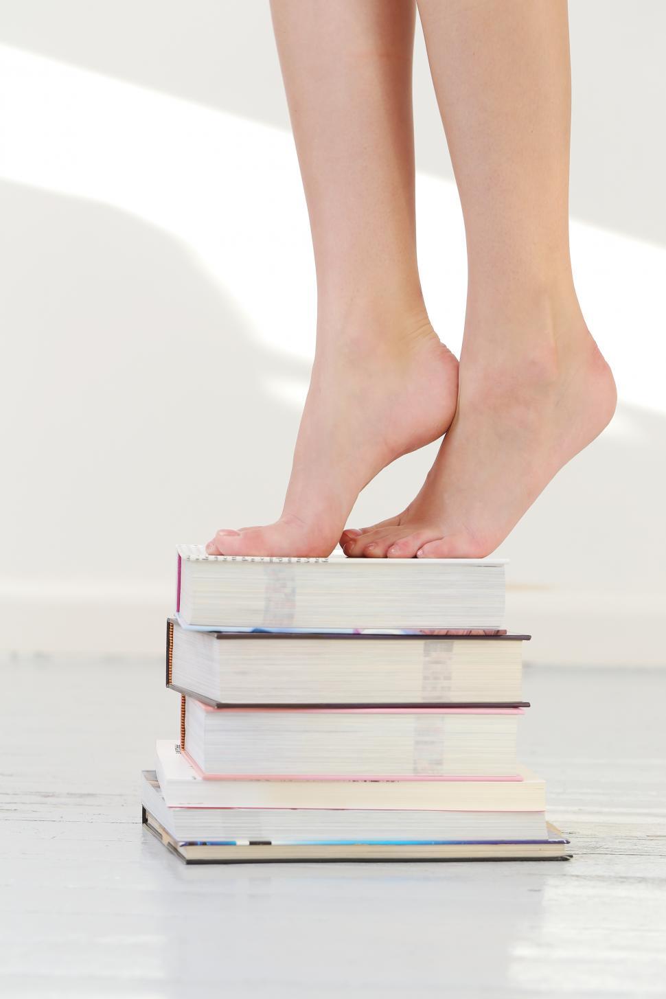 Free Image of Person standing on a stack of books 