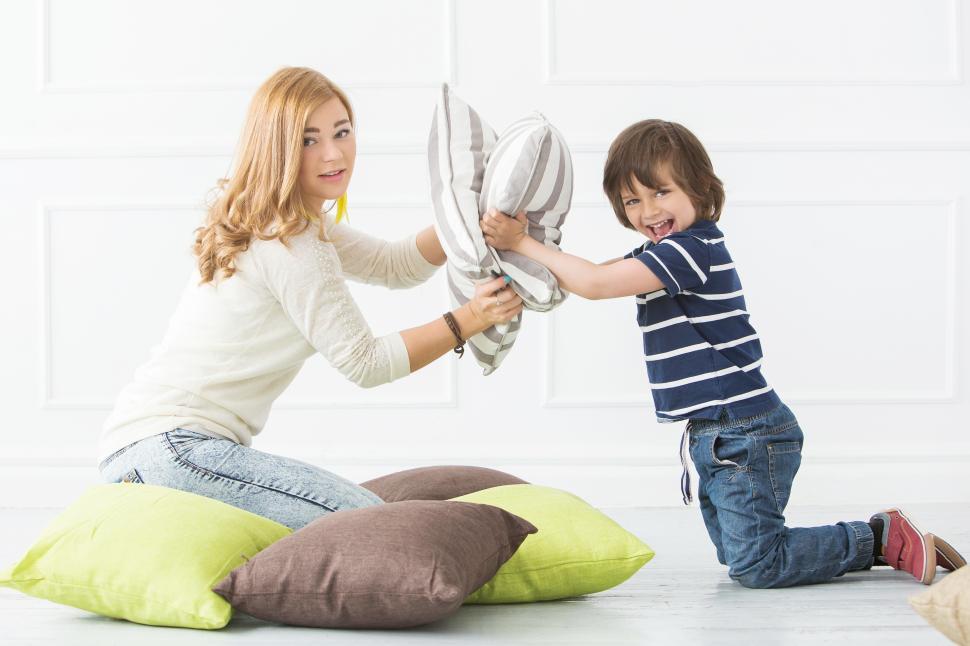 Free Image of Adorable kid in pillow fight with mother 
