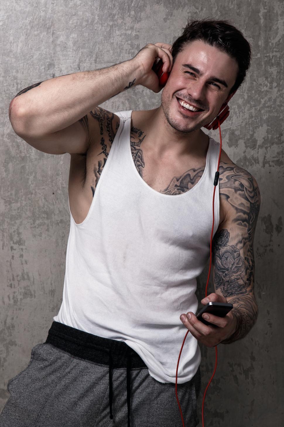 Free Image of Happy man with tattoos listening to music 