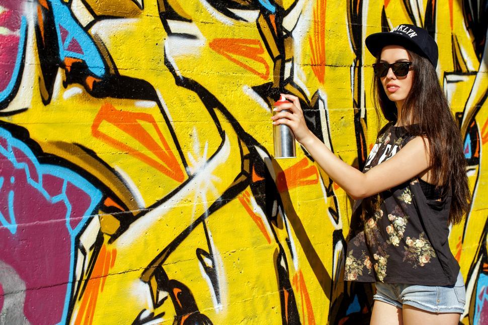 Free Image of Girl with can of spray paint and graffiti wall 