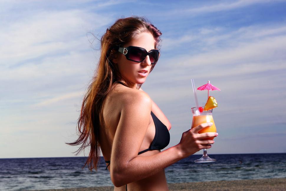 Free Image of young and beautiful girl on the beach with fruity drink 