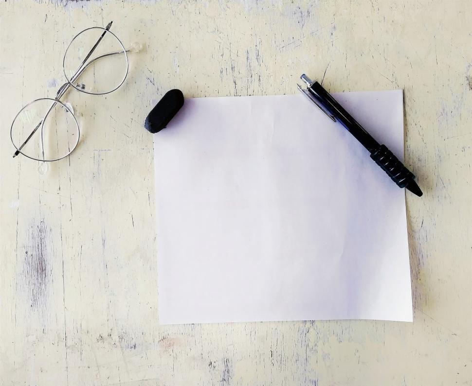 Free Image of Glasses, paper, pencil and eraser on a desk  