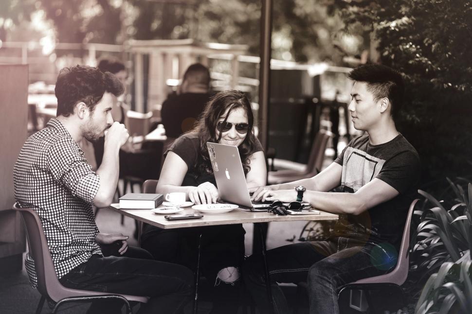 Free Image of Friends Smiling and Working with Laptops at a Cafe Terrace 