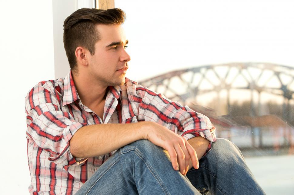Free Image of Young casual guy sitting in on a window sill 