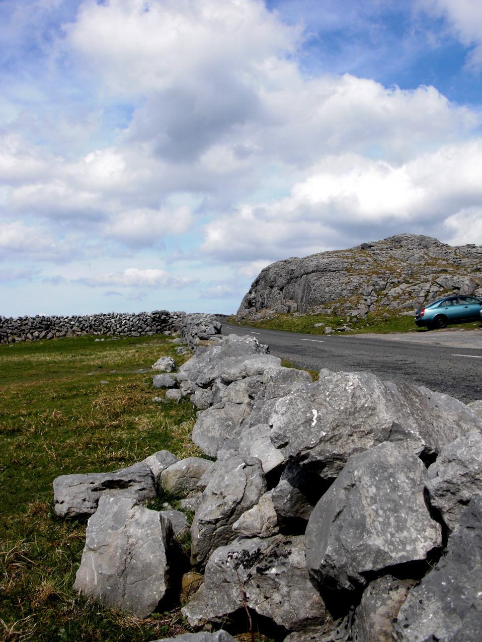 Free Image of Car Driving Down Road Next to Rock Wall 