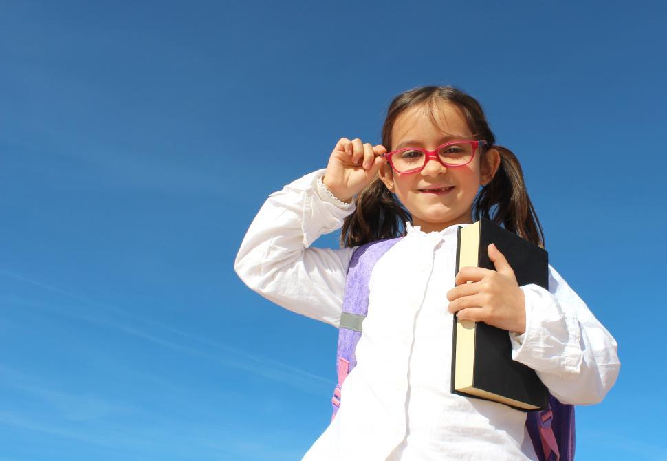 Free Image of Portrait of Cute Little Girl with Book Straightening Glasses - E 