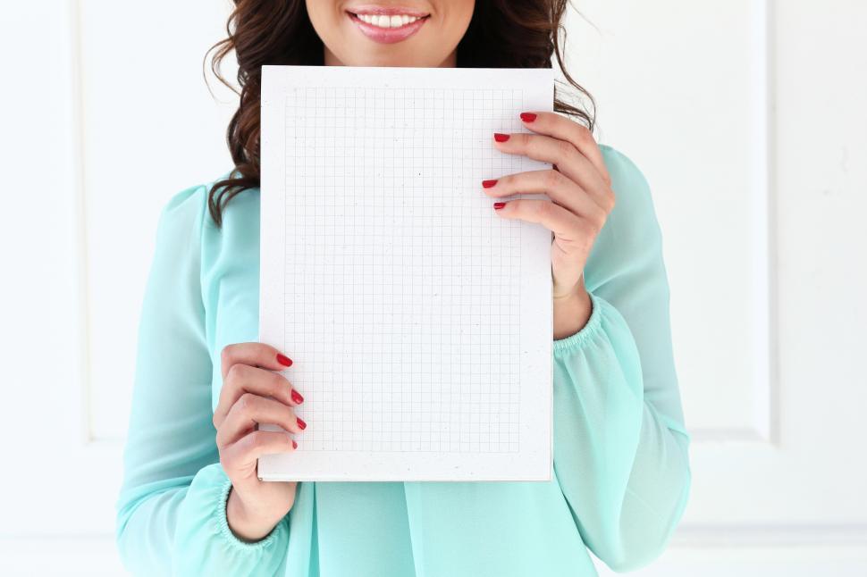 Free Image of Anonymous smiling woman holding blank grid notebook paper 