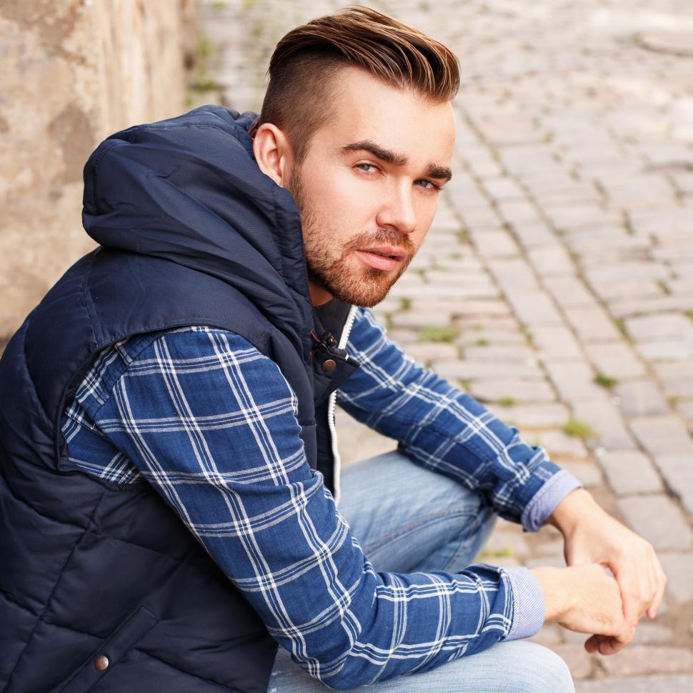 Download Free Stock Photo of Man sitting on the street, looking over his shoulder 