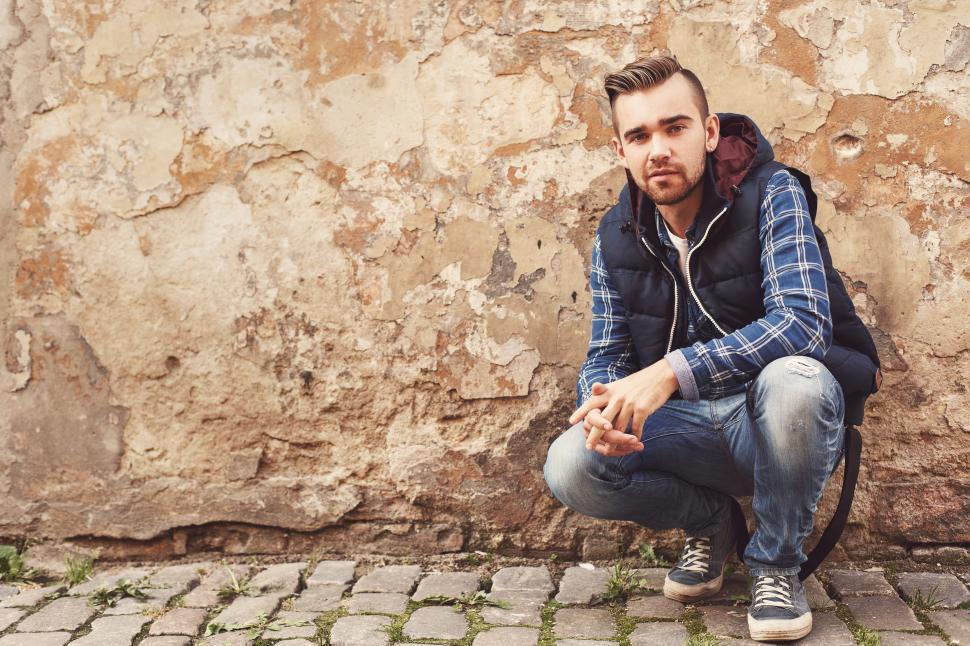 Free Image of Young man crouching on the street, looking at the camera 