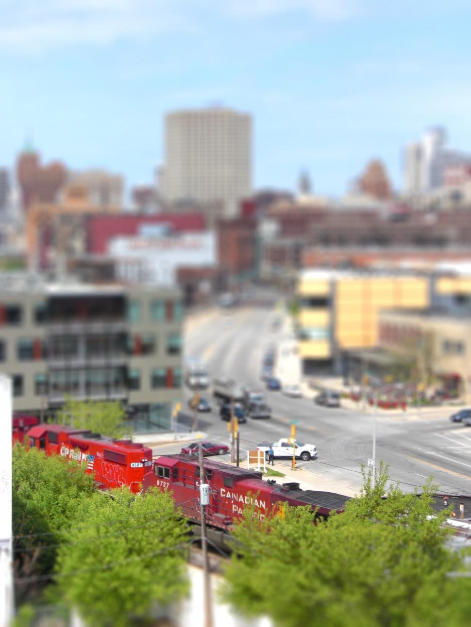 Free Image of Red Train Traveling Through City Near Tall Buildings 