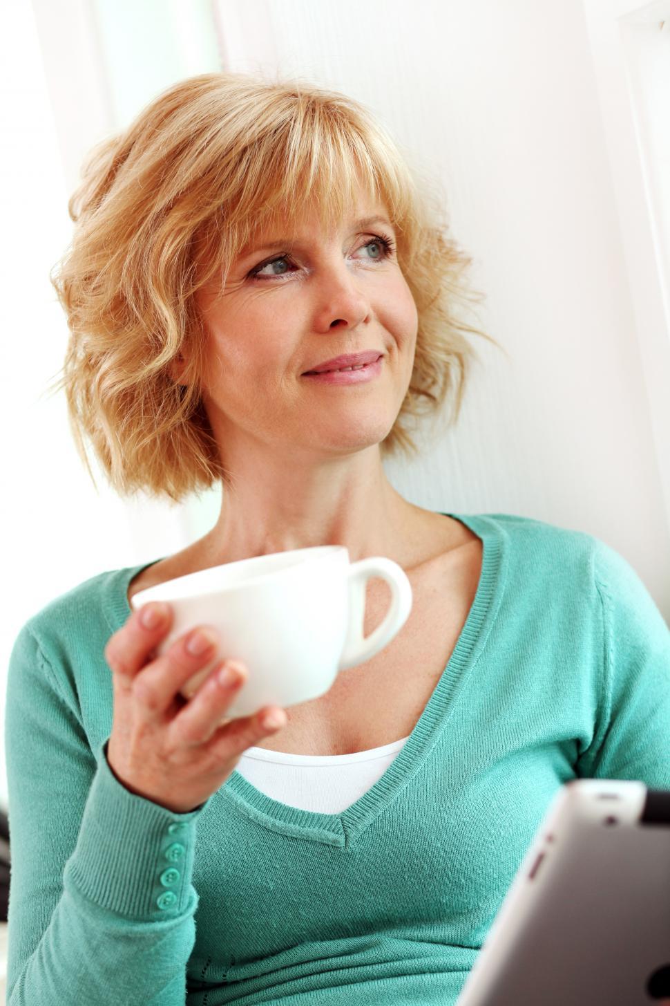 Free Image of Middle aged woman relaxing with coffee and tablet device 