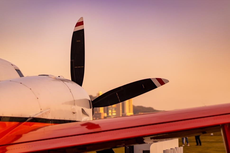 Free Image of Propeller Plane Parking on green grass in a sunset city background  